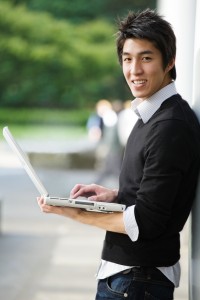 A shot of an asian student working on his laptop at the campus