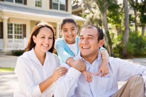 Portrait happy Hispanic family sitting with house in background